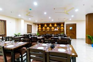 a restaurant with wooden tables and chairs and a chef in the background at Hotel Sagar Sonnet in Haldia