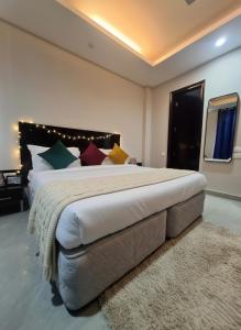 a large bedroom with a large bed with colorful pillows at Hotel Giri Prime Inn Near Cyber City, Phase 3 Metro in Gurgaon +9 photos