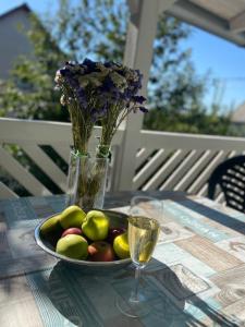a plate of fruit on a table with a vase of flowers at Panoráma Vendégház in Igal