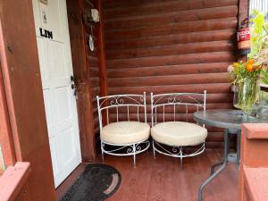 a porch with two chairs and a table and a door at בקתות עץ סקנדינביות במטולה in Metulla