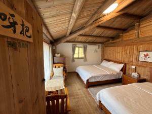 a bedroom with two beds in a room with wooden walls at Horn Seaside Homestay in Nangan