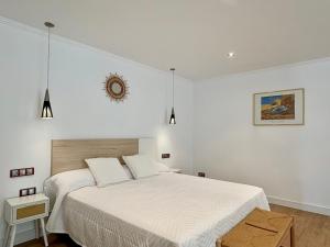 a white bedroom with a bed and a clock on the wall at Villa Sa Punta in Cala en Blanes
