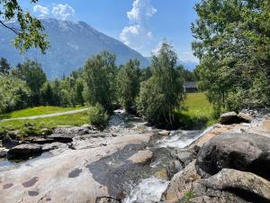 a river with rocks and trees and a mountain at The house by the waterfall in Breim
