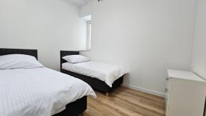 two beds in a room with white walls and wooden floors at Fieldorfa House in Ostrołęka