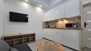 a kitchen with white cabinets and a tv on the wall at Fieldorfa House in Ostrołęka +40 photos
