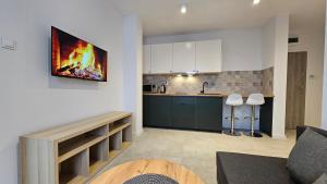 a living room with a kitchen with a fire painting on the wall at Fieldorfa House in Ostrołęka
