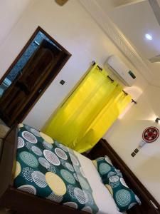a bedroom with a bed and a yellow curtain at Hôtel Okpèyèmi in Porto-Novo