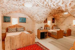 a bedroom with two beds and a stone wall at Kasr-ı Kikan Hotel in Mardin