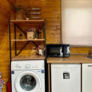 a kitchen with a washing machine and a microwave at Cottage and sauna hill silence mestia 2 in Mestia