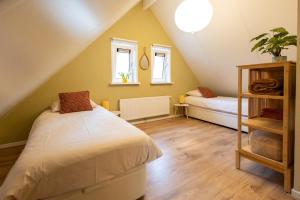 a attic bedroom with a bed and a couch at Vakantiehuis Vliegend Hert Veluwe in Nunspeet
