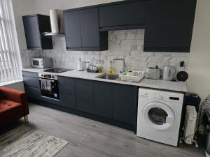 a kitchen with a sink and a washing machine at Stylish 1 & 2 Bed Apartment - Desborough - Kettering - Sleeps up to 5 - Free Parking, - WIFI - Contractors, Professionals, Families and Relocators - By The Home Makers Hub in Kettering