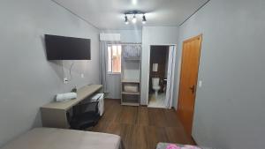 a room with a bed and a desk with a television at Hotel Majestic in Pelotas