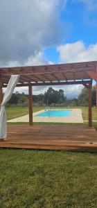 a wooden pavilion with a pool in the background at Chacra Dosvistas in Maldonado