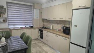 a kitchen with white cabinets and a table with green chairs at Zanora apartment's in Aiud