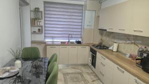 a kitchen with white cabinets and a table with green chairs at Zanora apartment's in Aiud