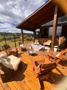 a wooden deck with chairs and tables and a pavilion at Flor da serra in Urubici