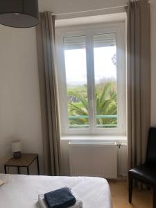 a bedroom with a window and a bed and a chair at Villa plaisance in Plomodiern