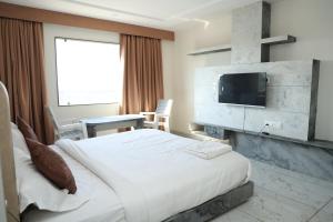 a hotel room with a bed and a flat screen tv at Hotel Magnet in Indore