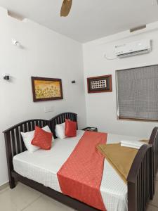 a bedroom with a bed with red and white pillows at Ashirvad Homes in Mannārakkāt