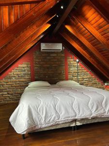 a bedroom with a white bed in a brick wall at Chale do Morro in Marques de Sousa