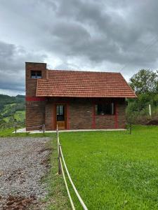 a small brick house with a grass field and a fence at Chale do Morro in Marques de Sousa
