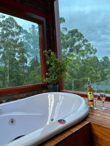 a bath tub sitting next to a window with wine glasses at Chale do Morro in Marques de Sousa +18 photos