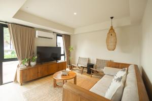 a living room with a couch and a tv at ELYSIUM Villa Khao Lak in Khao Lak