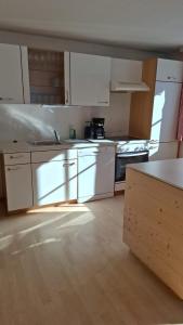 a kitchen with white cabinets and a wooden floor at Ferienhaus Schindeler in Mellau +33 photos