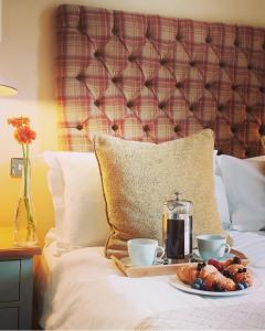 a tray of food on a bed with two cups and a coffee maker at The Lansdowne Boutique Rooms with Breakfast - Adults Only in Bourton on the Water +92 photos