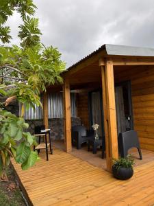 a wooden deck with chairs and tables on a cabin at Le ptit Chalet du bonheur in Entre-Deux