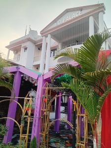 a building with a purple structure with palm trees in front at Virat Palace in Deoghar