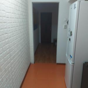 a hallway with a white brick wall and a refrigerator at Two-room apartment in Drăgăşani