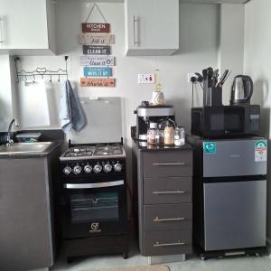 a small kitchen with a stove and a microwave at Spacious Studio Apartment with Swimming pool in Nairobi