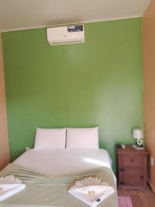 a bedroom with a bed with a green wall at Chalé da Pousada Avalon Célia in Alto Paraíso de Goiás