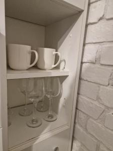 a shelf with cups and wine glasses on it at Dream Loft in Kłodzko +3 photos