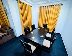 a dining room with a table and chairs and yellow curtains at Mist Cave Ella in Etimale