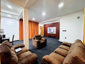 a living room with couches and a flat screen tv at Mist Cave Ella in Etimale