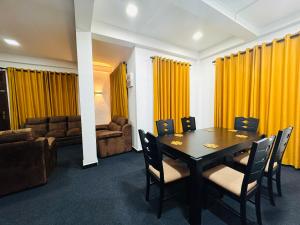 a dining room with yellow curtains and a table and chairs at Mist Cave Ella in Etimale