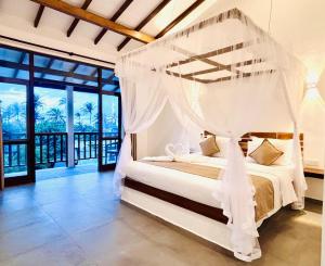 a bedroom with a bed with a mosquito net at Hotel Siyomin in Ahangama