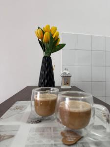 two cups of coffee on a table with a vase of flowers at AG Apartman in Kraljevo +6 photos