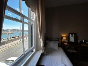 a bedroom with a bed and a large window at Admiral MacBride Bed & Breakfast in Plymouth