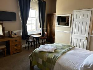 a bedroom with a bed and a desk and a window at Admiral MacBride Bed & Breakfast in Plymouth