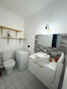 a white bathroom with a toilet and a sink at L'Échappée Bleue Sea view studio in Moule in Le Moule +12 photos