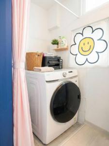 a washing machine in a room with a smile sign on the wall at 자자쿨스테이 in Seoul