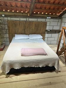 a bed with a pink pillow on top of it at Chalé Orquídea com vista para as montanhas in Palmeiras