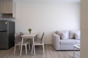 a living room with a white couch and a table and chairs at The Hampton Suites Bangna in Bangna