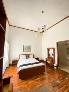 ein Schlafzimmer mit einem Bett und einem Holzboden in der Unterkunft Concordia Hotel Bumi Sangkuriang Bandung in Bandung + 20 Fotos