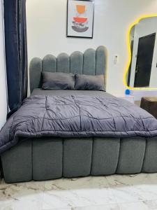 a bed with a purple comforter in a room at OS Dominion Homes in Mama