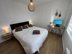 a bedroom with a white bed and a desk with a computer at La villa caroline in Léon