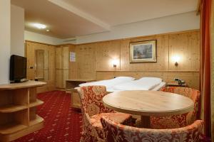 una camera d'albergo con due letti, un tavolo e delle sedie di Hotel Ronce a Ortisei